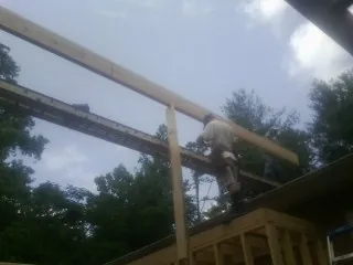 Carpenter setting a ridge beam over a new addition frame — Ice Dam Removal by Roofing Brothers in Anton