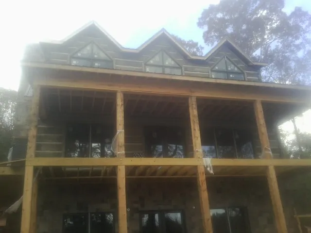 Dormers and porch framing on a large log home under construction — Roof Coating work by our crew in Anton