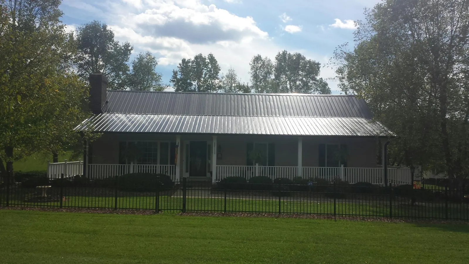 Gray metal roof on a brick ranch with a full width front porch — Gutter Guard Installation work by our crew in Anton