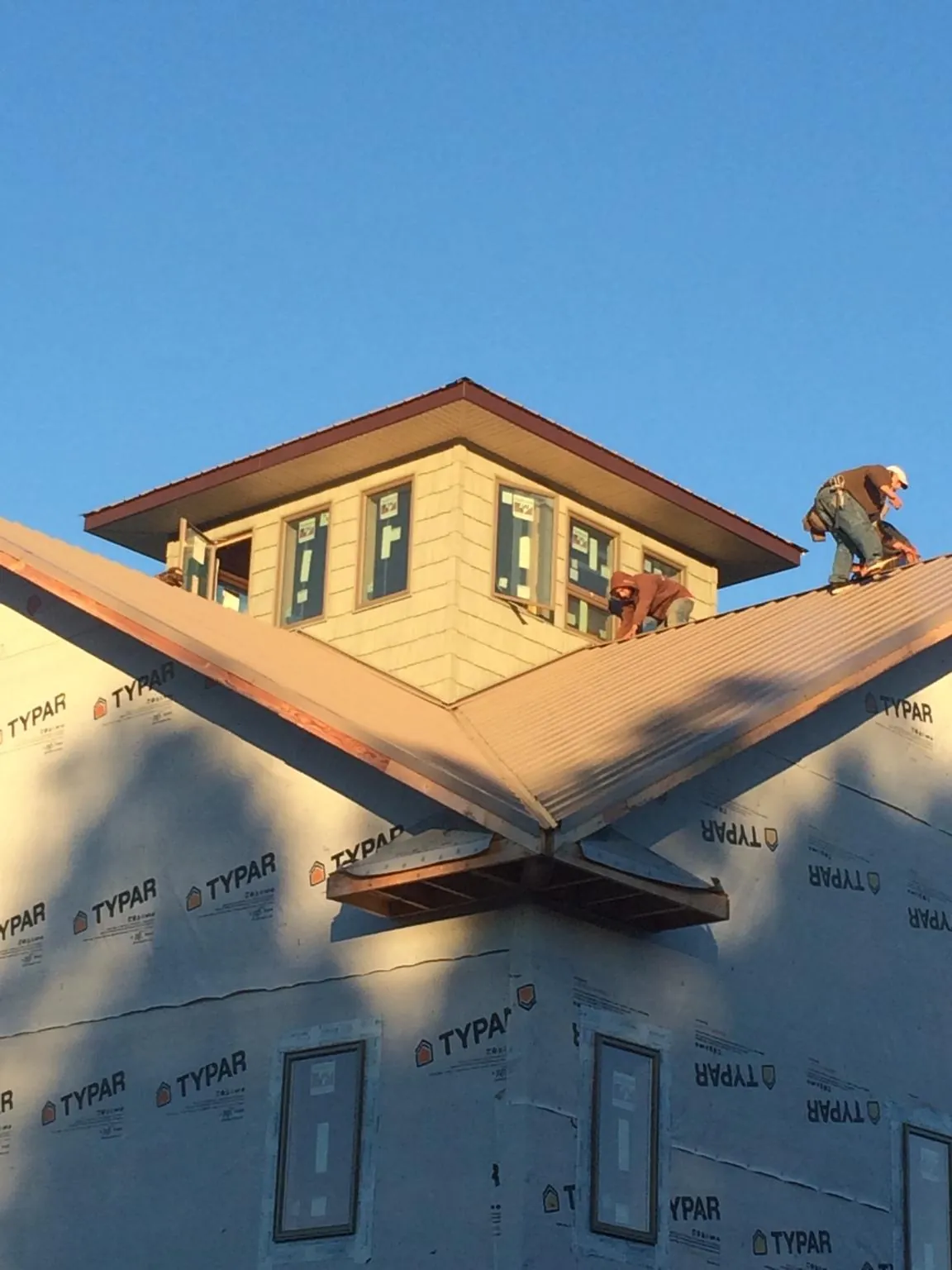 Roofers working around a rooftop cupola on a new metal roof at sunset — Roof Waterproofing in Anton by Roofing Brothers